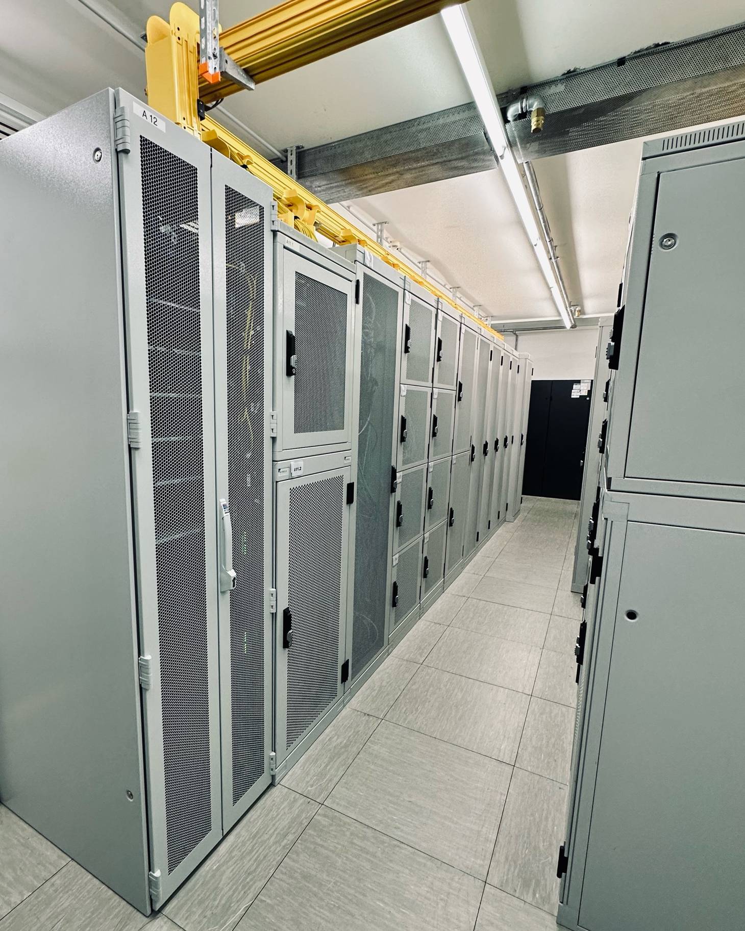 Reihe heller Serverschränke mit Kabeltrassen in unserem Rechenzentrum